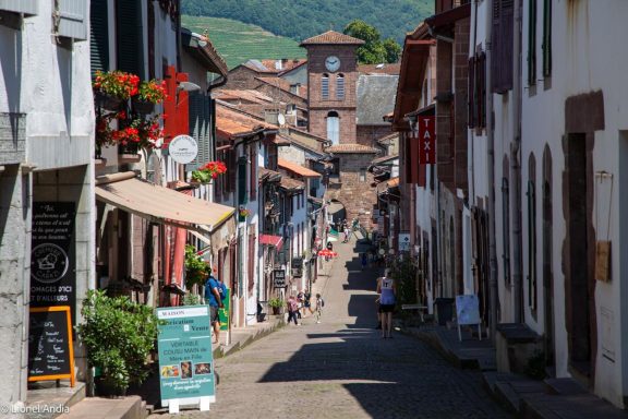 Schmale Straße durch einen historischen Ort mit bunten Häuserfassaden und Geschäften