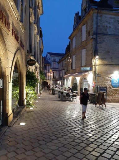 Historische französische Altstadt mit beleuchteten Steinhäusern, Kopfsteinpflaster und kleinen Restaurants am Abend