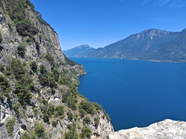 Gardasee-Panorama – Felslandschaft bei Tremosine Blick von einer steilen Felswand auf den tiefblauen Gardasee und die umliegenden Berge