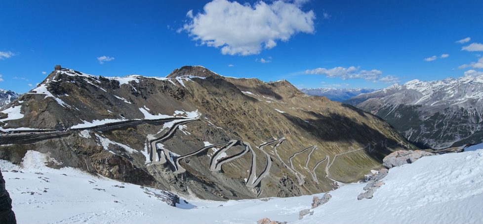 Stilfser Joch – Motorradtour Dolomiten & Gardasee 2027 Kurvenreiche Passstraße am Stilfser Joch in den italienischen Alpen mit schneebedeckten Berghängen