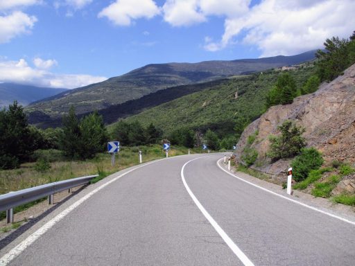Kurvenreiche Bergstraße durch grüne Täler und bewaldete Berghänge der Pyrenäen